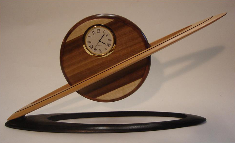Large Saturn Clock - 13" long x 7" high x 3" deep - Poplar (or burl) disc, Cherry ring, Ebonized Walnut base.  Small version - 7"long x 5" high x 2" deep.